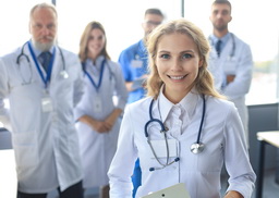 lady doctor with stethoscope around her neck standing surrounded by her colleagues in lab coats at a hospital